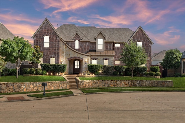 1270 Timber Ln, Frisco, TX 75036 - french country home featuring a standing seam roof, brick siding, a front yard, a shingled roof, and stone siding