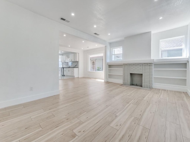 809 Cristler Ave, Dallas, TX 75223 - unfurnished living room featuring light wood-style floors, baseboards, a brick fireplace, and recessed lighting