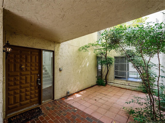 12605 Burninglog Ln, Dallas, TX 75243 - doorway to property featuring stucco siding and a patio area