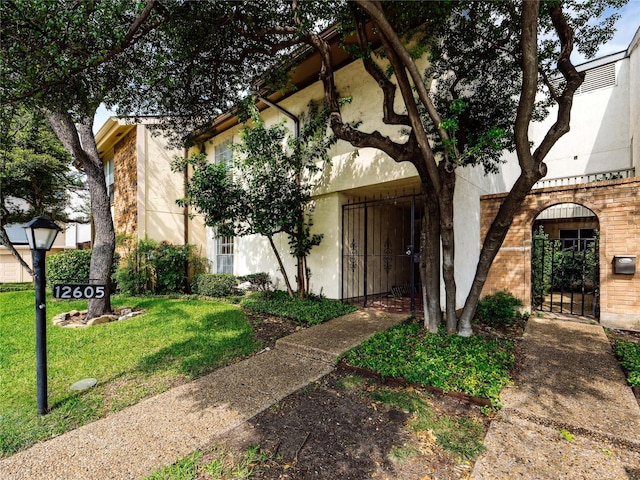 12605 Burninglog Ln, Dallas, TX 75243 - view of front of home featuring stucco siding, a front lawn, and a gate