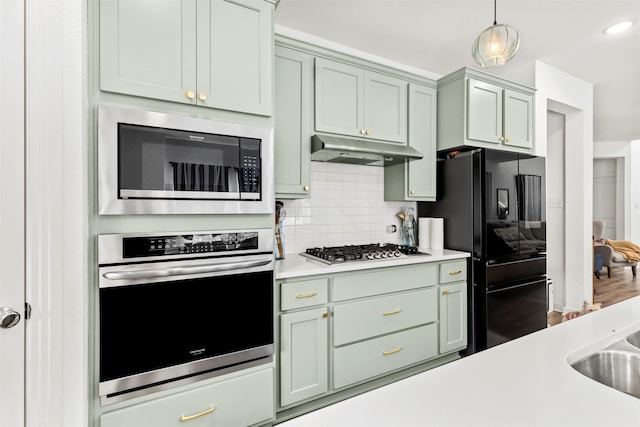 3942 Oak Crk, Denison, TX 75020 - kitchen with stainless steel appliances, under cabinet range hood, light countertops, tasteful backsplash, and hanging light fixtures