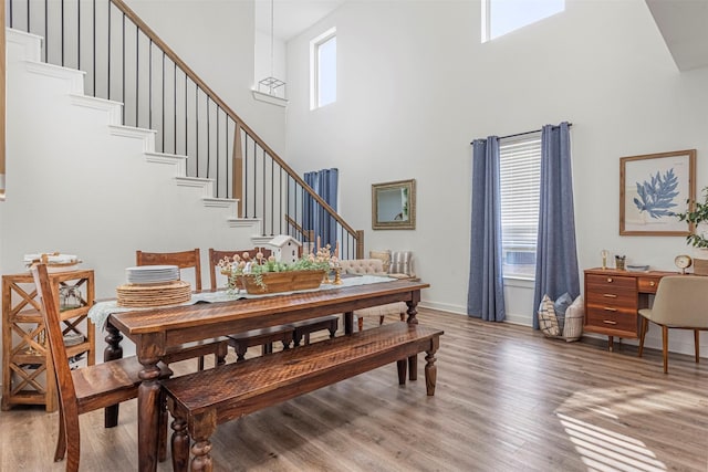 3942 Oak Crk, Denison, TX 75020 - dining room featuring a towering ceiling, stairway, light wood-style flooring, and baseboards