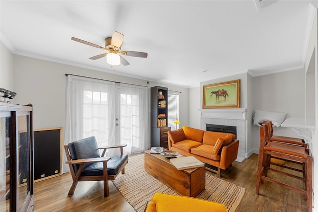 8400 Hickory St Unit 103, Frisco, TX 75034 - living area featuring a tiled fireplace, wood finished floors, a ceiling fan, and ornamental molding