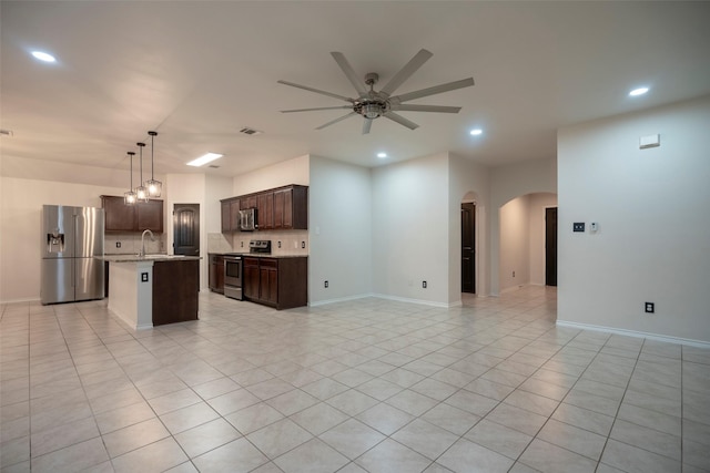 1543 Meadowlake Dr, Waxahachie, TX 75165 - kitchen with appliances with stainless steel finishes, arched walkways, open floor plan, a ceiling fan, and dark brown cabinetry