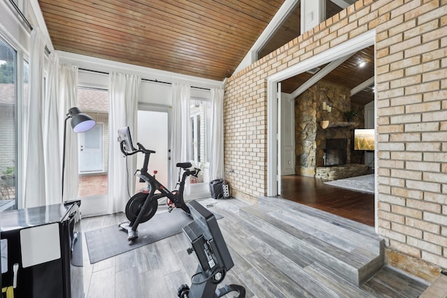 8820 Hunters Glen Trl, Fort Worth, TX 76120 - exercise area featuring wood ceiling, a stone fireplace, wood finished floors, vaulted ceiling, and brick wall
