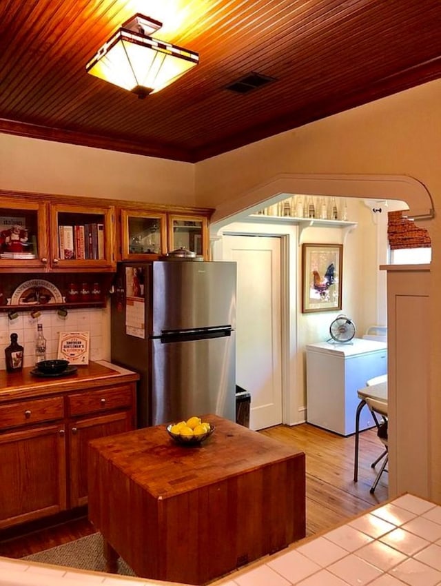 1001 S Locust St, Clarksville, TX 75426 - kitchen featuring freestanding refrigerator, butcher block countertops, washer / clothes dryer, light wood finished floors, and glass insert cabinets
