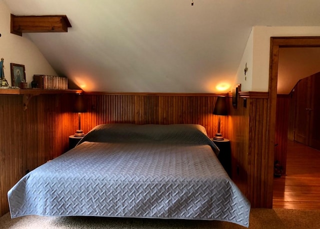 1001 S Locust St, Clarksville, TX 75426 - bedroom with vaulted ceiling, a wainscoted wall, wood finished floors, and wood walls