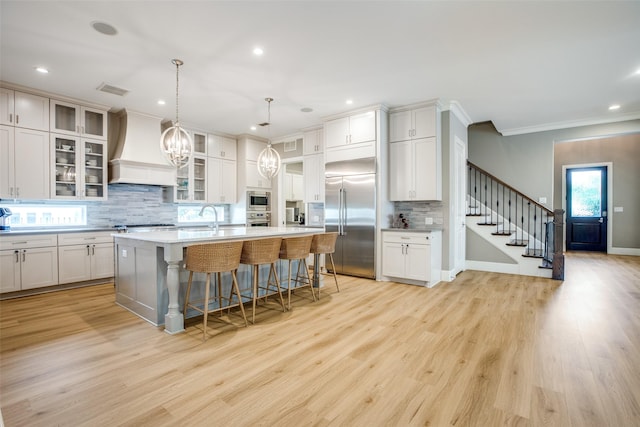 6009 Westchester Ln, Frisco, TX 75034 - kitchen featuring built in appliances, premium range hood, light countertops, decorative backsplash, and a kitchen bar