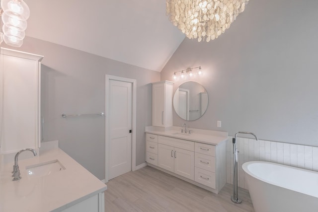 415 Saddle Tree Trl, Coppell, TX 75019 - bathroom with two vanities, a freestanding bath, lofted ceiling, wood finished floors, and a chandelier