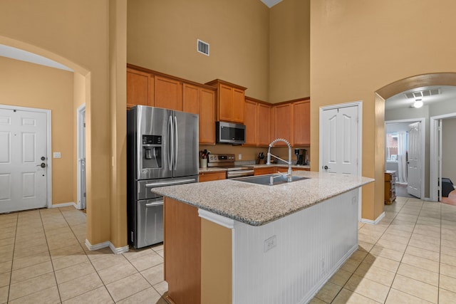 632 Shotwell St, Crowley, TX 76036 - kitchen featuring appliances with stainless steel finishes, a towering ceiling, a sink, arched walkways, and light tile patterned floors