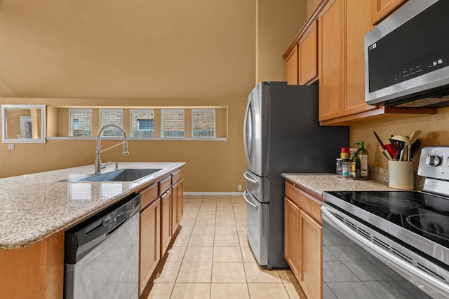 632 Shotwell St, Crowley, TX 76036 - kitchen featuring appliances with stainless steel finishes, a sink, light stone counters, a center island with sink, and light tile patterned flooring