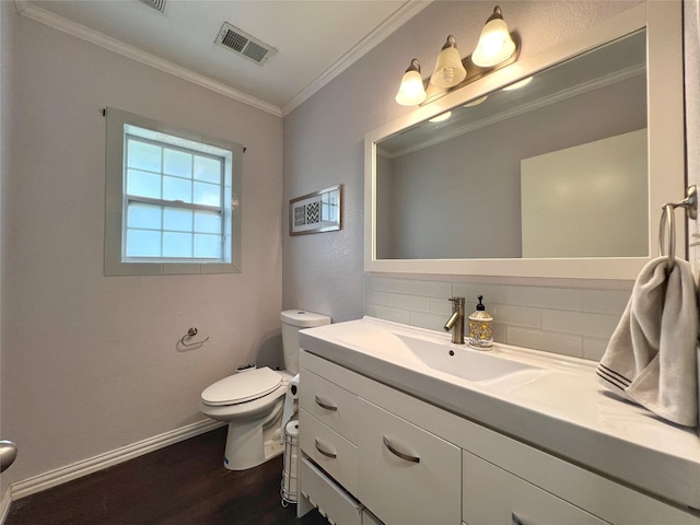 half bathroom featuring wood finished floors, crown molding, toilet, backsplash, and baseboards