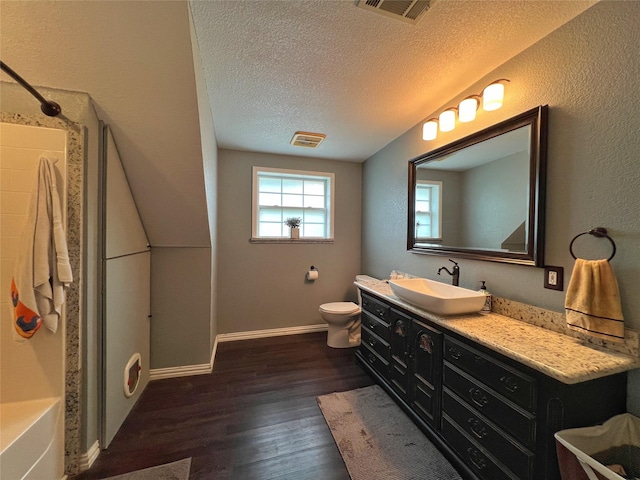full bathroom with a textured ceiling, a shower, wood finished floors, baseboards, and toilet