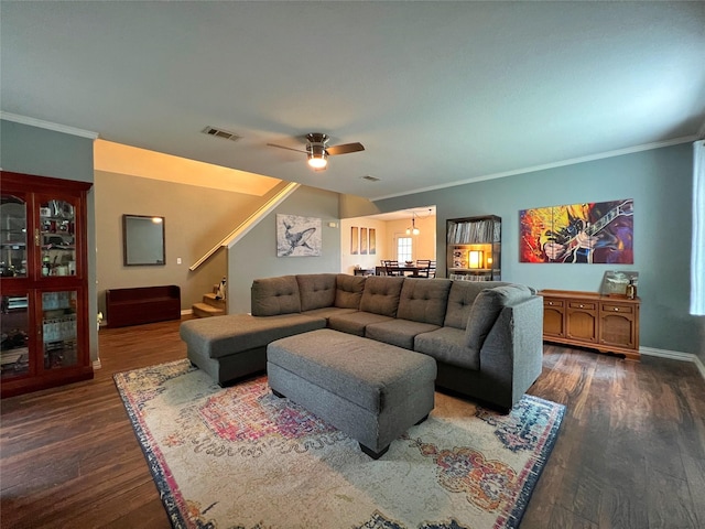 living area with dark wood-type flooring, crown molding, ceiling fan, stairway, and baseboards
