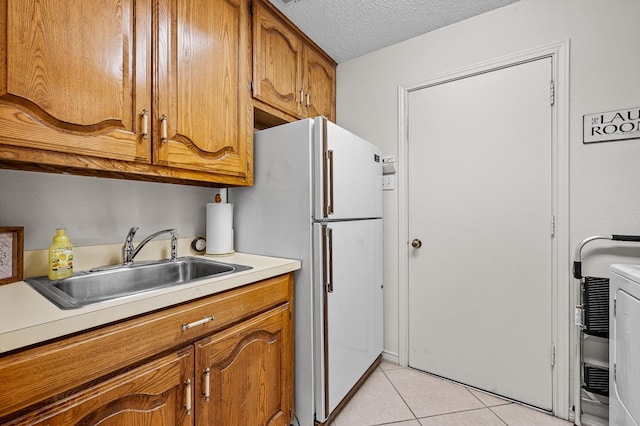 4006 Thornhill Way, Rowlett, TX 75088 - kitchen featuring a sink, brown cabinets, light countertops, light tile patterned flooring, and freestanding refrigerator