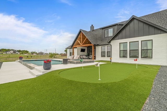 5219 Old Dennis Rd, Weatherford, TX 76087 - rear view of house featuring an area to practice putting, board and batten siding, a patio area, roof with shingles, and a pool with connected hot tub