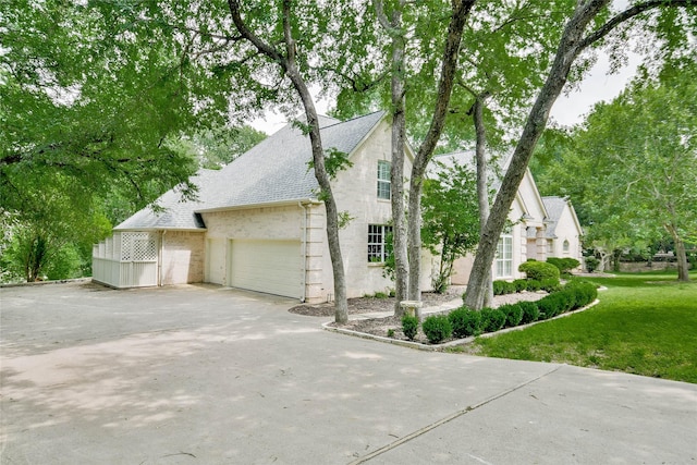 7712 Ravenswood Rd, Granbury, TX 76049 - view of property exterior with roof with shingles, brick siding, driveway, a lawn, and an attached garage