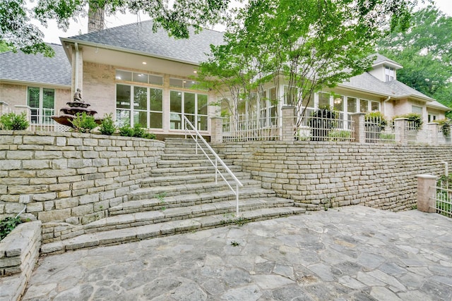 7712 Ravenswood Rd, Granbury, TX 76049 - back of property with brick siding, a shingled roof, a patio area, and stairs