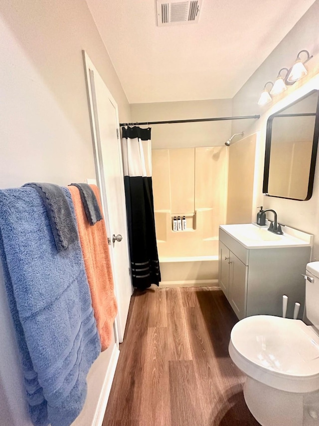 full bathroom with wood finished floors, shower / tub combo with curtain, toilet, and vanity