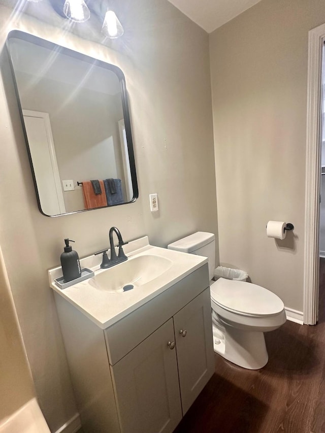 bathroom featuring wood finished floors, baseboards, toilet, and vanity
