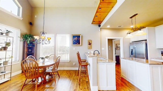 2807 Wind Point Ct, Tolar, TX 76476 - dining space with light wood-style flooring, a chandelier, baseboards, and a towering ceiling