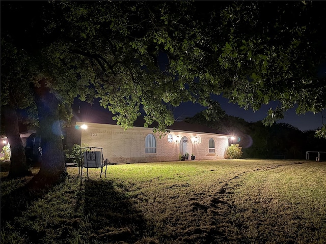 522 W 7th St, Weatherford, TX 76086 - back of house at night featuring a yard