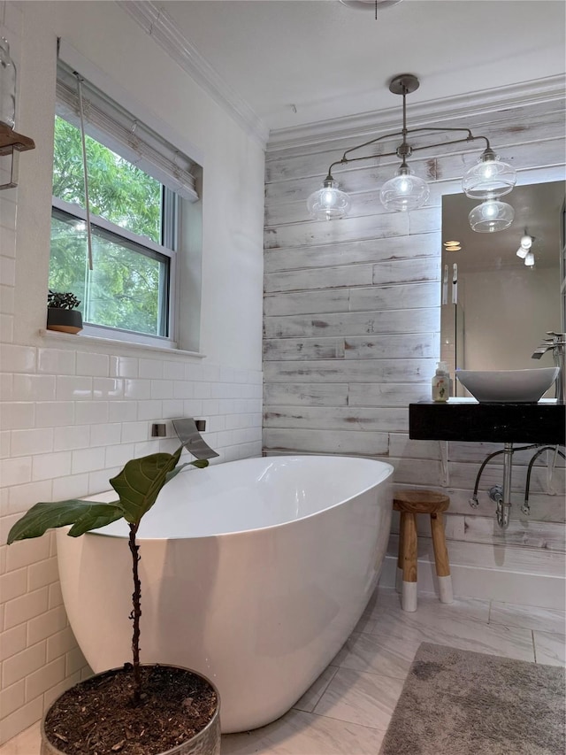 522 W 7th St, Weatherford, TX 76086 - bathroom featuring a freestanding tub, crown molding, tile walls, a sink, and marble finish flooring