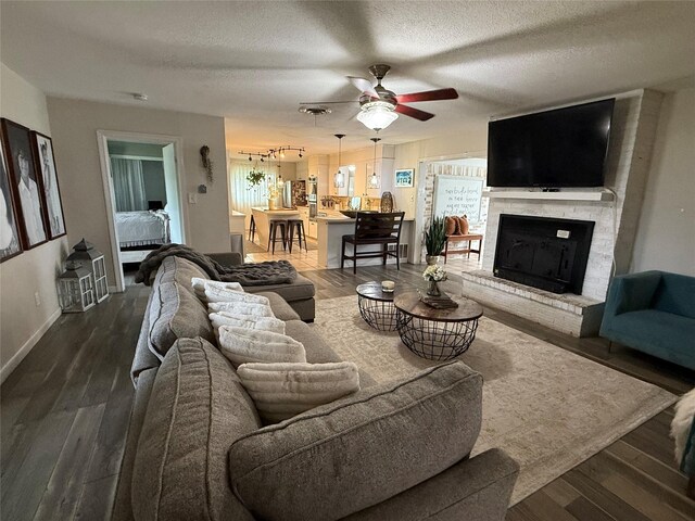522 W 7th St, Weatherford, TX 76086 - living room featuring a ceiling fan, a fireplace, a textured ceiling, dark wood-type flooring, and baseboards
