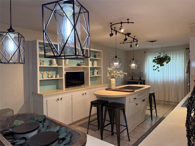 522 W 7th St, Weatherford, TX 76086 - kitchen with white cabinets, a kitchen island, a breakfast bar area, light countertops, and decorative light fixtures