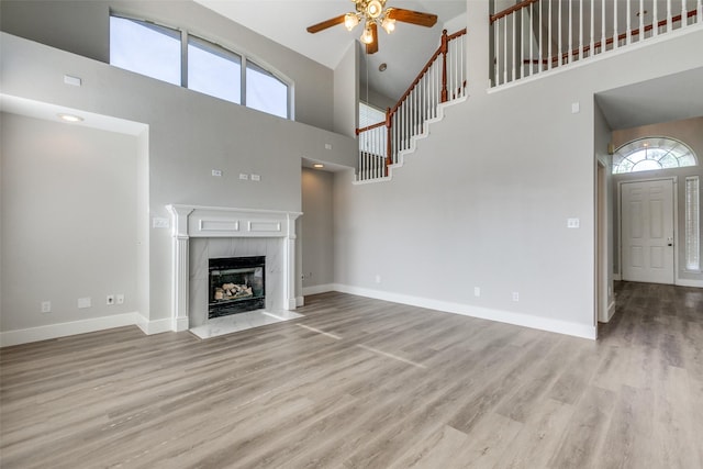 318 Mesquite Ct, Murphy, TX 75094 - unfurnished living room featuring a high ceiling, ceiling fan, wood finished floors, a fireplace, and baseboards