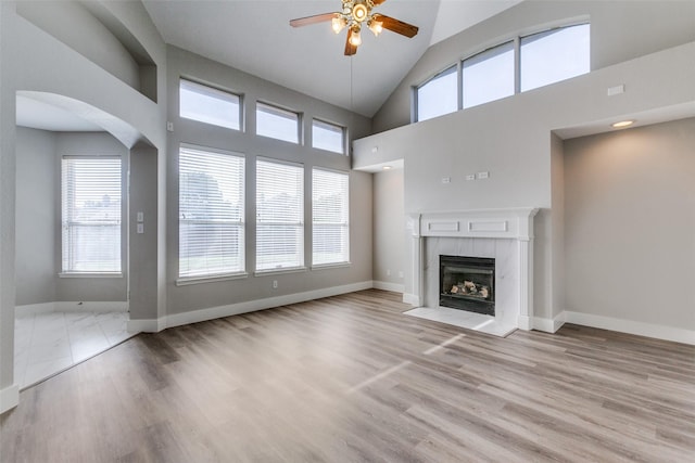 318 Mesquite Ct, Murphy, TX 75094 - unfurnished living room with ceiling fan, a tile fireplace, wood finished floors, baseboards, and high vaulted ceiling