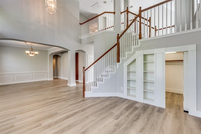318 Mesquite Ct, Murphy, TX 75094 - foyer entrance featuring arched walkways, a chandelier, a high ceiling, wood finished floors, and ornamental molding