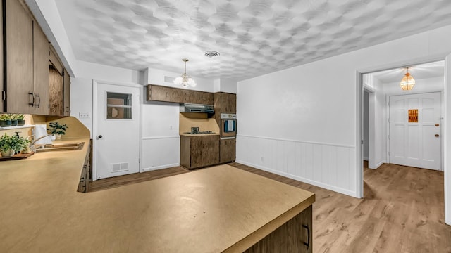 100 Oakhurst Dr, Hurst, TX 76053 - kitchen featuring oven, extractor fan, a sink, light wood finished floors, and decorative light fixtures