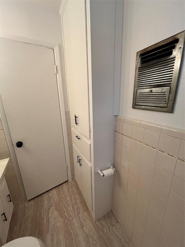 100 Oakhurst Dr, Hurst, TX 76053 - bathroom featuring tile walls, vanity, toilet, and a wainscoted wall
