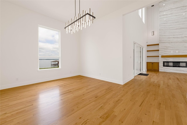 733 El Barco, Corsicana, TX 75109 - unfurnished dining area featuring light wood-style flooring, baseboards, a fireplace, and a chandelier
