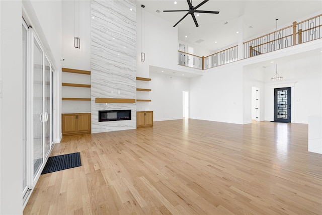 733 El Barco, Corsicana, TX 75109 - unfurnished living room featuring a towering ceiling, a premium fireplace, light wood finished floors, and ceiling fan