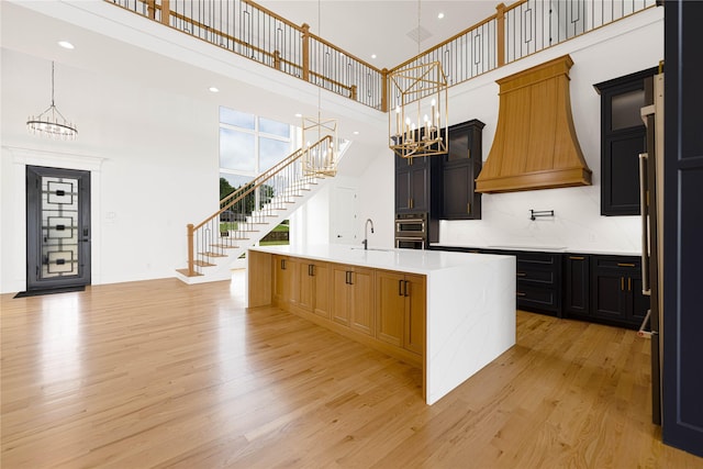 733 El Barco, Corsicana, TX 75109 - kitchen with a chandelier, light wood-style floors, a high ceiling, an island with sink, and light countertops