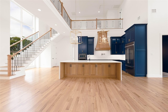 733 El Barco, Corsicana, TX 75109 - kitchen with custom exhaust hood, built in fridge, blue cabinetry, a towering ceiling, and light wood-type flooring