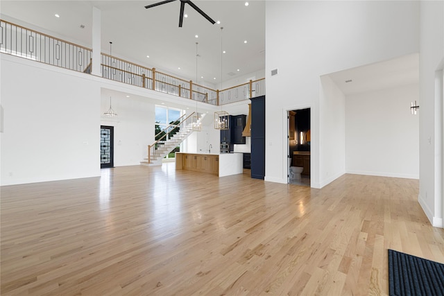 733 El Barco, Corsicana, TX 75109 - unfurnished living room with a high ceiling, a ceiling fan, light wood-style floors, stairway, and recessed lighting
