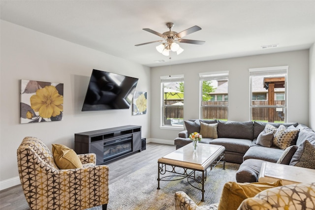 5909 Horsetail Dr, Mckinney, TX 75071 - living area featuring wood finished floors, baseboards, a ceiling fan, and a glass covered fireplace