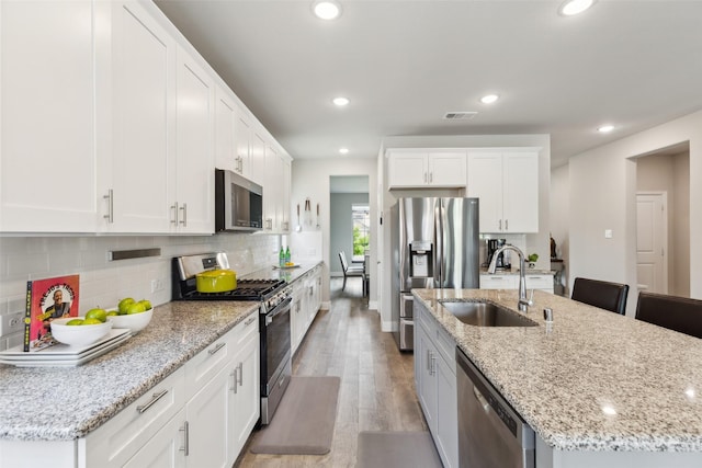 5909 Horsetail Dr, Mckinney, TX 75071 - kitchen featuring stainless steel appliances, a sink, an island with sink, light wood finished floors, and white cabinets