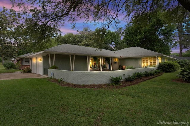 ranch-style house featuring a front yard, an attached garage, driveway, and brick siding