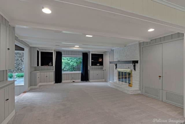 unfurnished living room with carpet flooring, beamed ceiling, healthy amount of natural light, and a fireplace