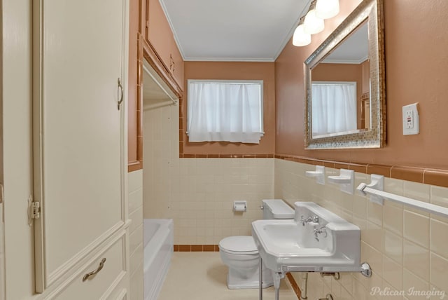 bathroom featuring toilet, tile walls, crown molding, a sink, and a wainscoted wall