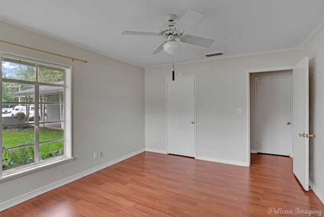 spare room featuring plenty of natural light, wood finished floors, ceiling fan, and crown molding
