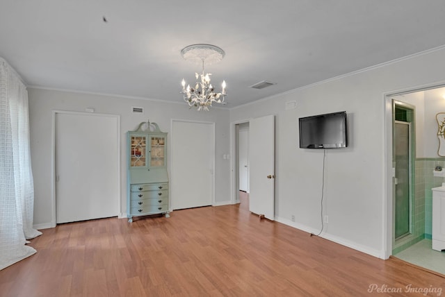 unfurnished living room with a chandelier, light wood-style floors, crown molding, and baseboards