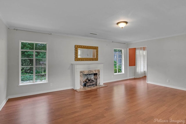 unfurnished living room with a fireplace, ornamental molding, wood finished floors, and baseboards