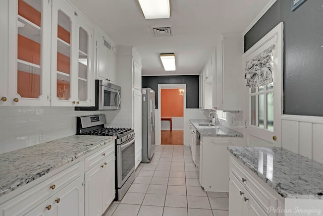 kitchen with stainless steel appliances, light tile patterned flooring, white cabinetry, and tasteful backsplash