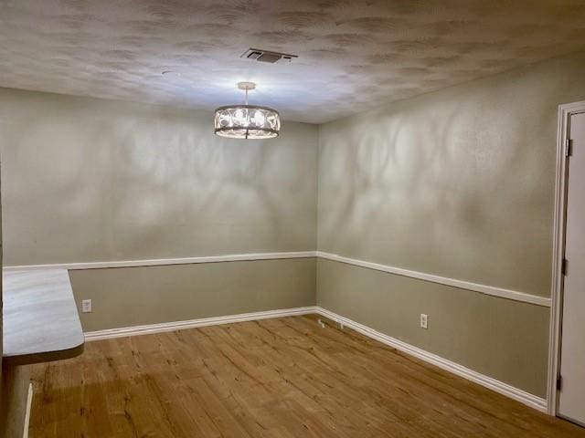 4916 Tracy Dr, Haltom City, TX 76117 - unfurnished dining area featuring wood finished floors, baseboards, a chandelier, and a textured ceiling