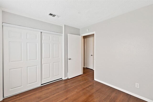 4208 Huckleberry Cir, Dallas, TX 75216 - unfurnished bedroom featuring dark wood-type flooring, baseboards, a closet, and a textured ceiling